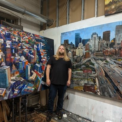 Adam O'Day standing between two of his Boston cityscape paintings