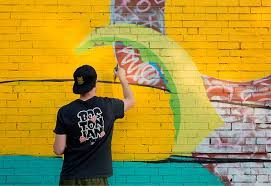 Croc spray painting a mural on a brick wall