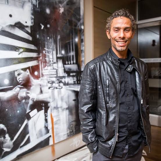 Percy Fortini-Wright standing in front of one of his portrait murals